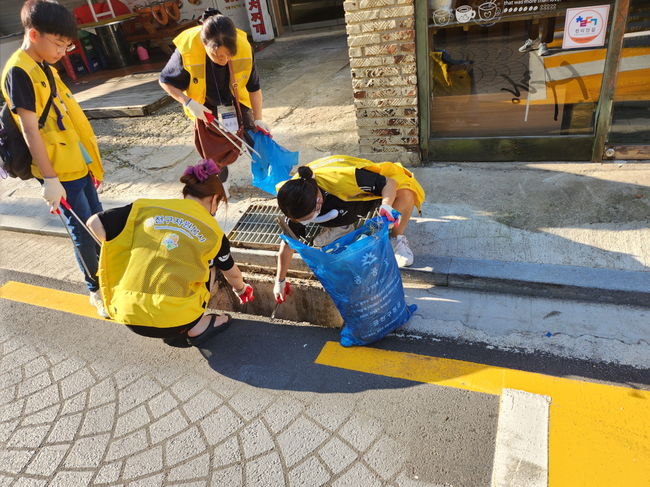 자원봉사자들이 빗물받이를 청소하고 있다