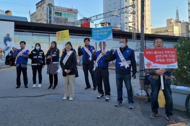 금연 어깨띠를 두르고 피켓을 이용해 흡연의 심각성을 알리고 있다.
